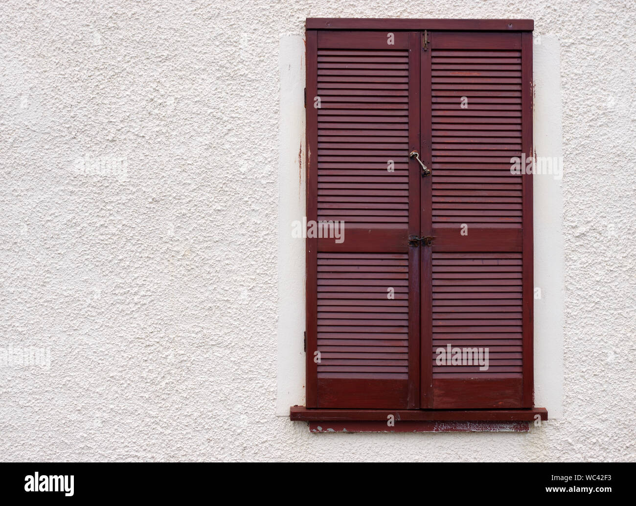 Braun Holzstäbchen Fensterläden in einem roh gegossen Wand Stockfoto