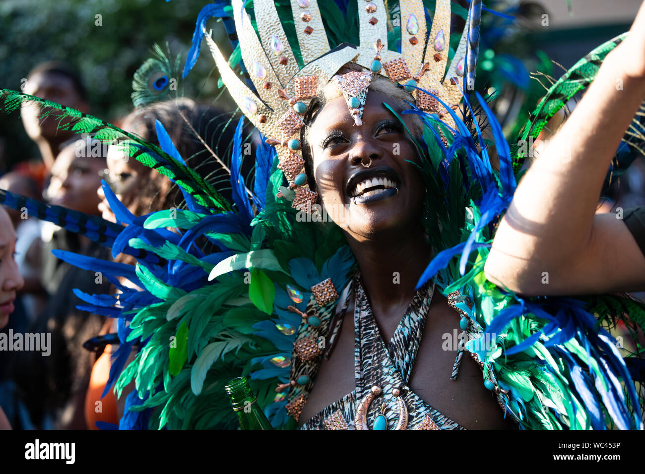 Performerin gekleidet in bunte Federn am Notting Hill Carnival, größte Karneval in Europa. Stockfoto