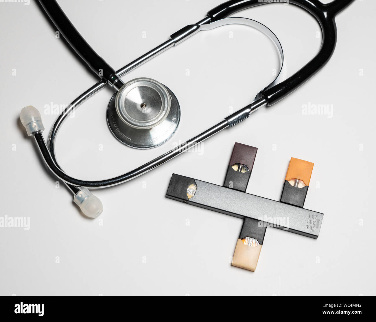 Box holding JUUL Nikotin Dispenser und Hülsen mit Stethoskop Stockfoto
