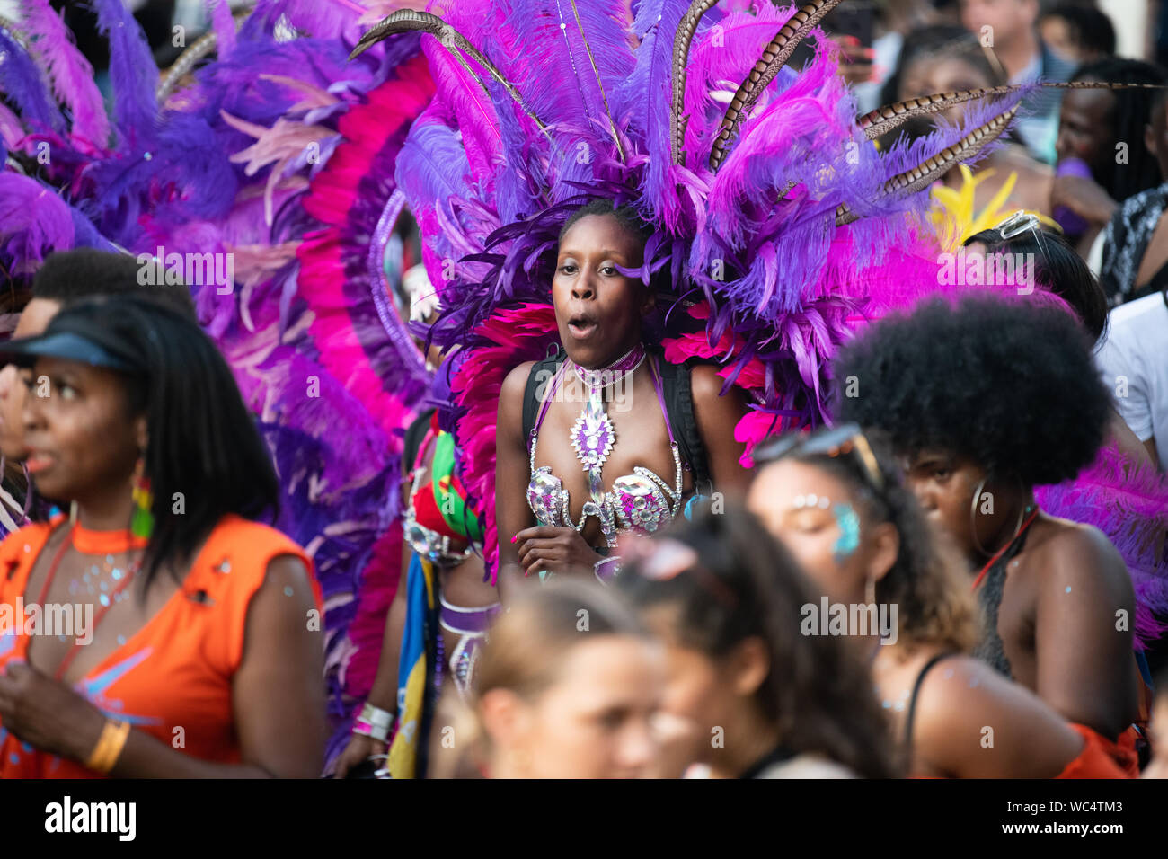 Performerin gekleidet in bunten Federn am Notting Hill Carnival, größte Karneval in Europa. Stockfoto