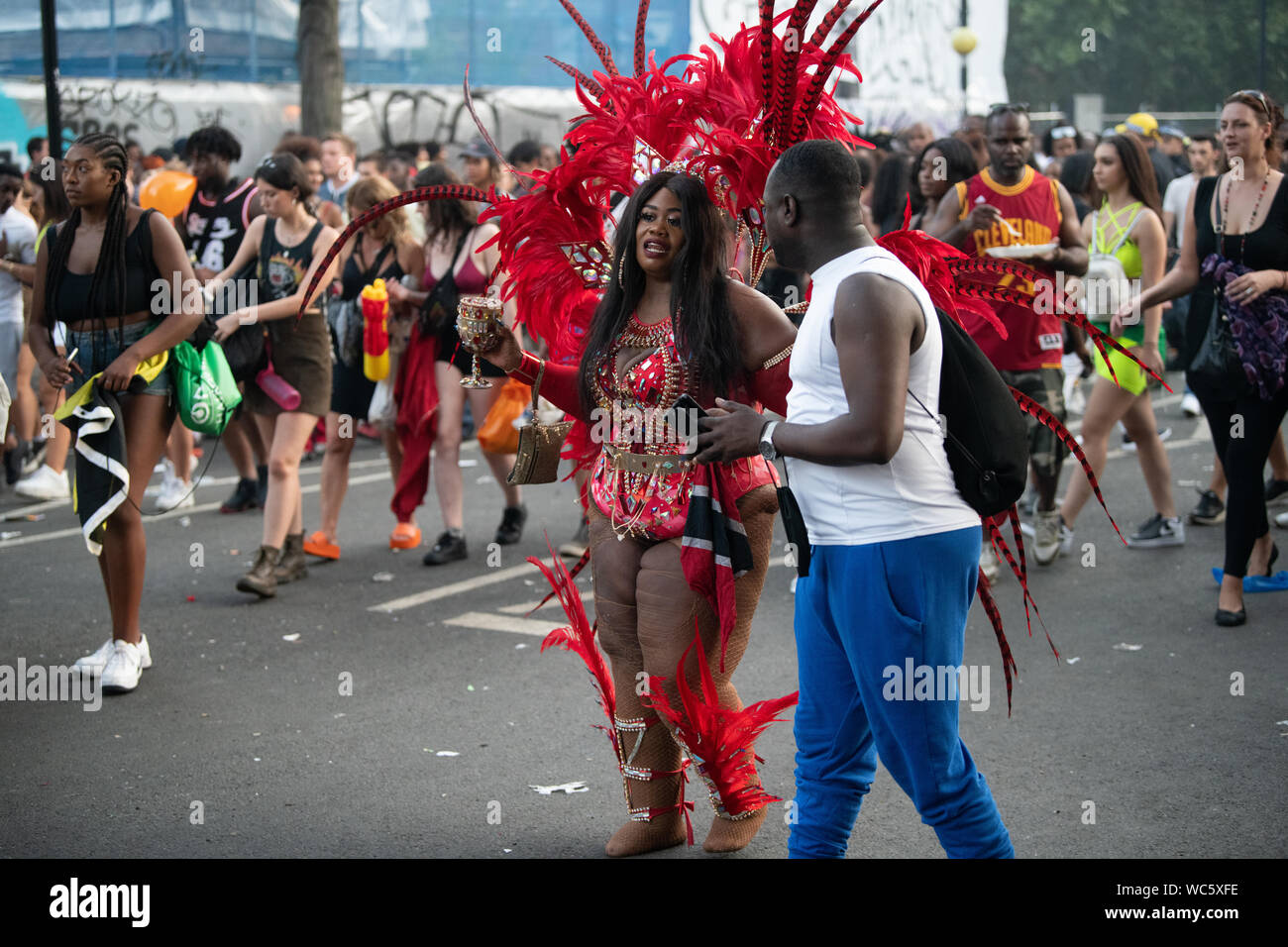 Ein Mann mit einem selfie mit einer Frau in der Notting Hill Carnival Gekleidet in rote Federn. Stockfoto
