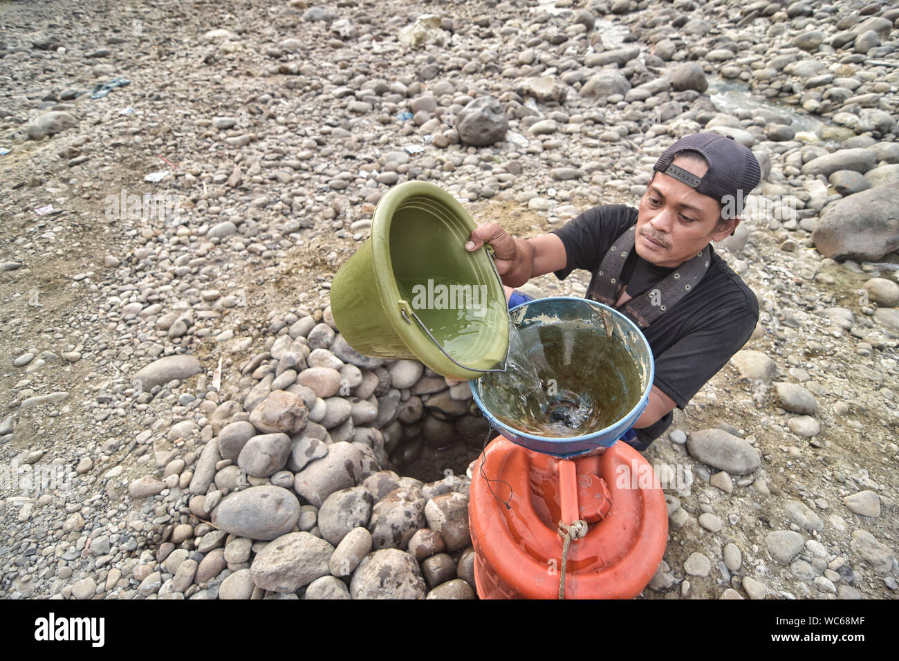 Bekasi, West Java, Indonesien. 27 Aug, 2019. Ein Bewohner sammelt das Wasser aus einem trockenen Cipamingkis Fluss für den häuslichen Gebrauch als ihre Brunnen Austrocknen infolge der Trockenheit im Sommer. der Meteorologie, Klimatologie und Geophysik Agentur hat davor gewarnt, dass die trockene Jahreszeit kann trockener und intensiver als im letzten Jahr aufgrund der El NiÃ±o Phänomen. Die Agentur klassifiziert, West Java, Central Java, die meisten Teile von Ost Java, Jakarta, Bali und Nusa Tenggara, da der Bereich der meisten anfällig für extreme Dürre, oder mehr als 60 Tage ohne Regen. Credit: Agung Fatma Putra/SOPA Images/ZUMA Draht/Alamy leben Nachrichten Stockfoto