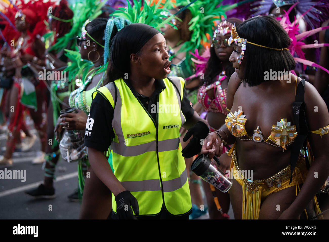 Synterna Sicherheit Steward im Gespräch mit dem Karneval am Notting Hill Carnival durchgeführt. Andere Darsteller im Hintergrund Stockfoto