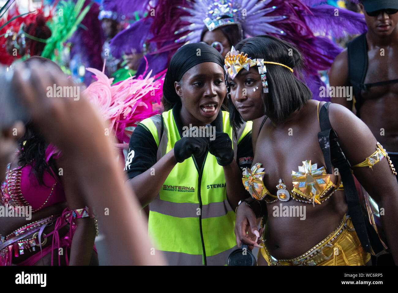 Synterna Sicherheit Steward im Gespräch mit dem Karneval am Notting Hill Carnival durchgeführt. Andere Darsteller im Hintergrund Stockfoto