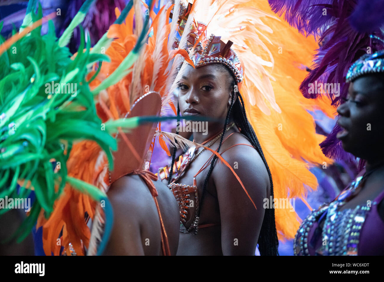 Tänzerin Federn tragen und Blick in die Kamera bei der Notting Hill Carnival in London, der größten Straße Karneval in Europa. Stockfoto