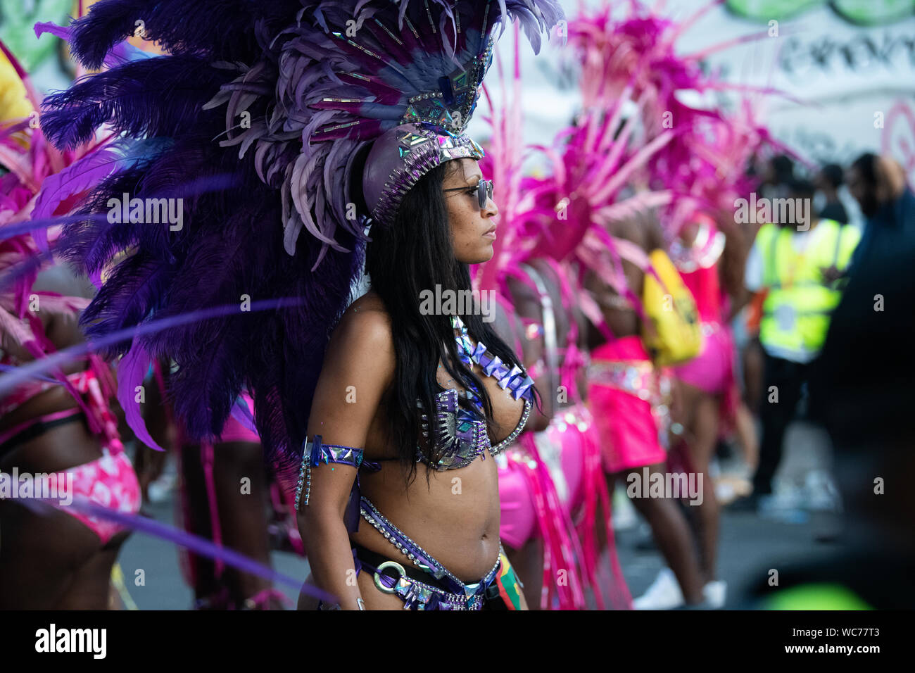Tänzerin Federn tragen und Blick in die Kamera bei der Notting Hill Carnival in London, der größten Straße Karneval in Europa. Stockfoto