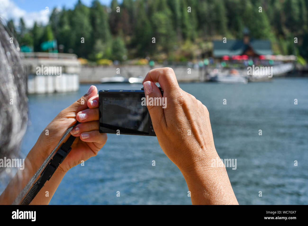 Eine Frau mit sparkle Nagellack zielt darauf ab, eine Kamera auf Boote entlang am See marina Stockfoto