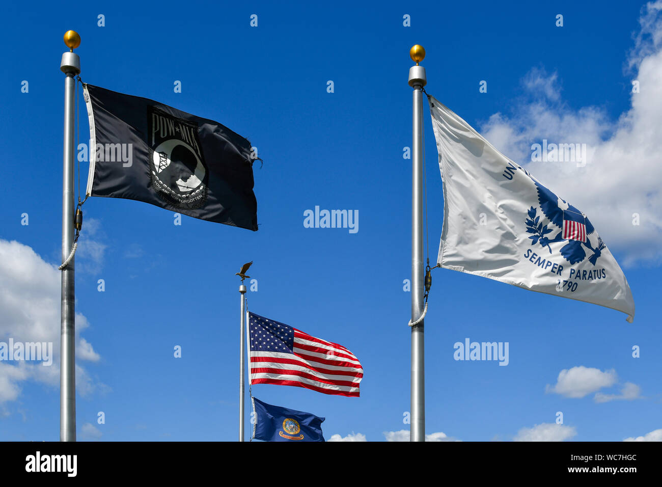 Bewaffneten dienst Fahnen wehen in der Nähe der amerikanischen Flagge einschließlich der Marine Semper Paratus logo. Die MIA-POW-Flag für Missing in Action und Kriegsgefangenen Stockfoto