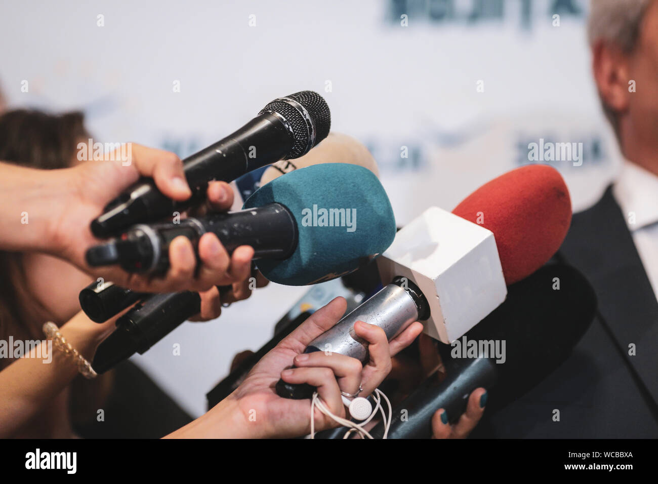 Details mit den Händen von Journalisten halten abgenutzt Mikrofone vor einem Politiker bei einer Pressekonferenz Stockfoto