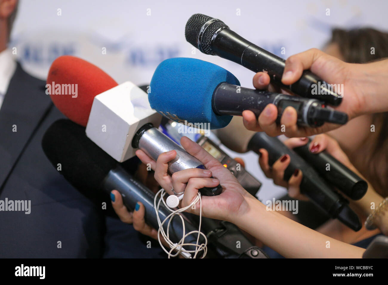 Details mit den Händen von Journalisten halten abgenutzt Mikrofone vor einem Politiker bei einer Pressekonferenz Stockfoto