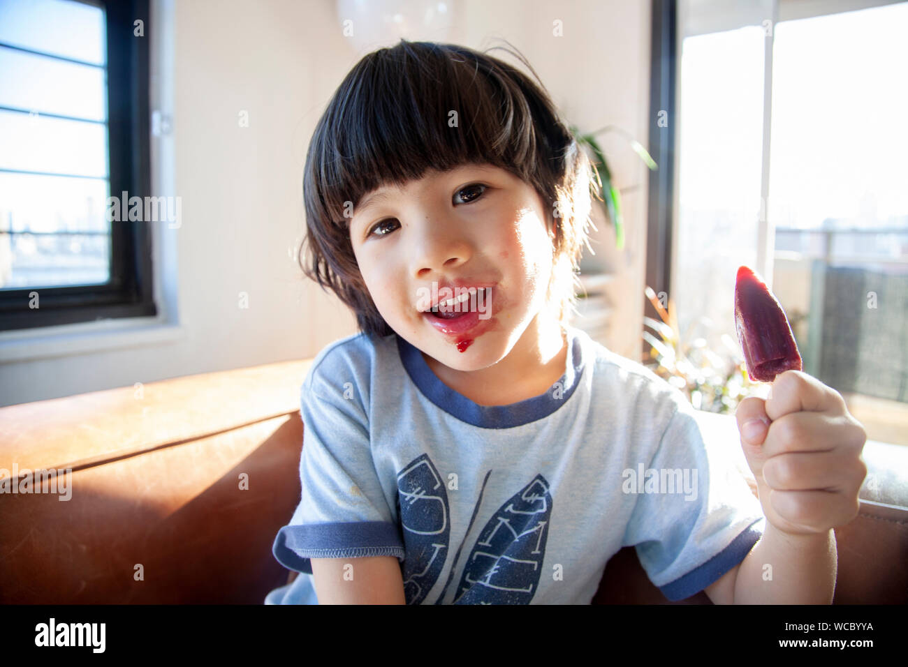 Multi-ethnische Junge 4-6 Jahre alt mit Eis pop im Innenbereich Stockfoto