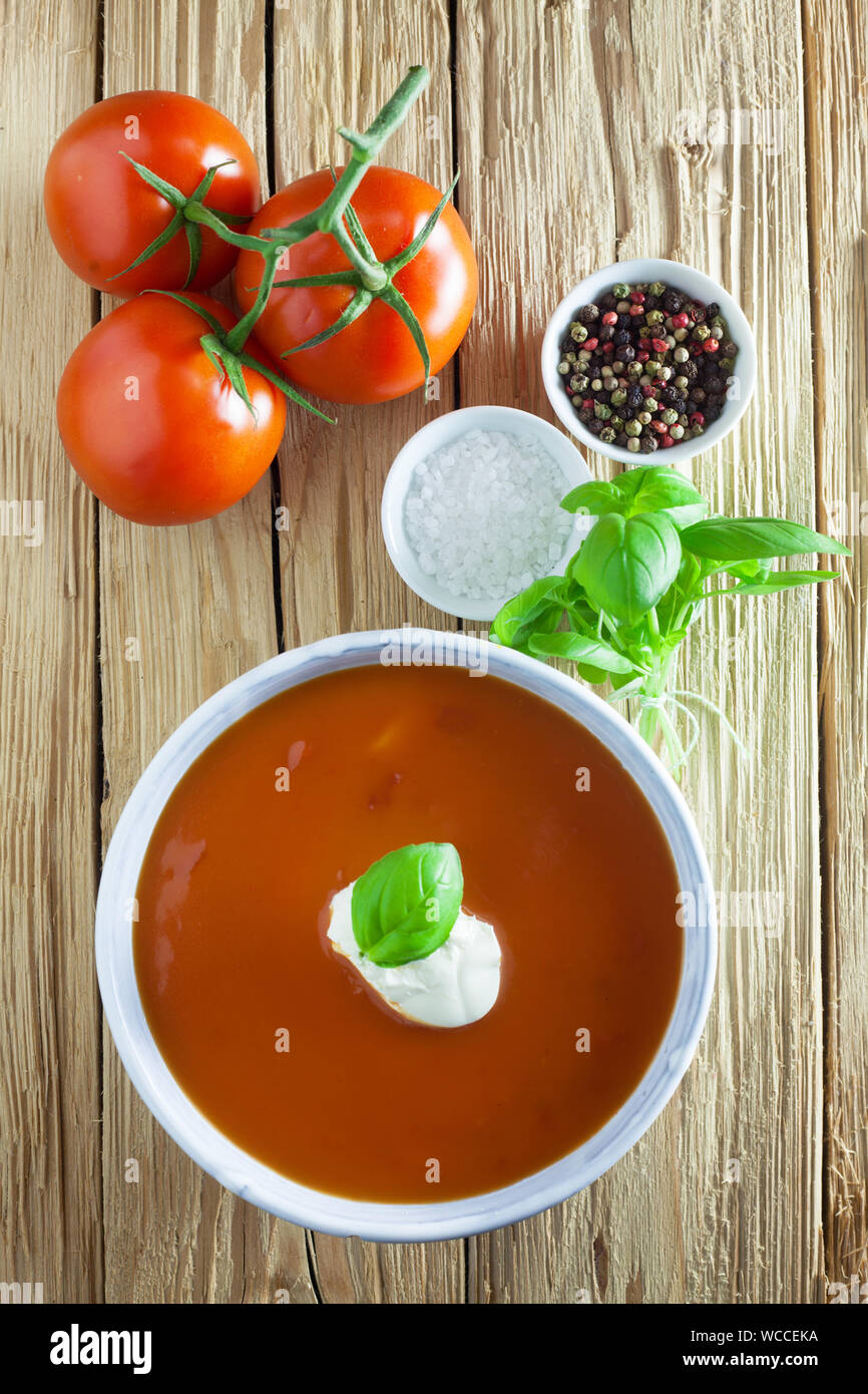 Tomatensuppe mit Zutaten auf einem hölzernen Hintergrund Stockfoto