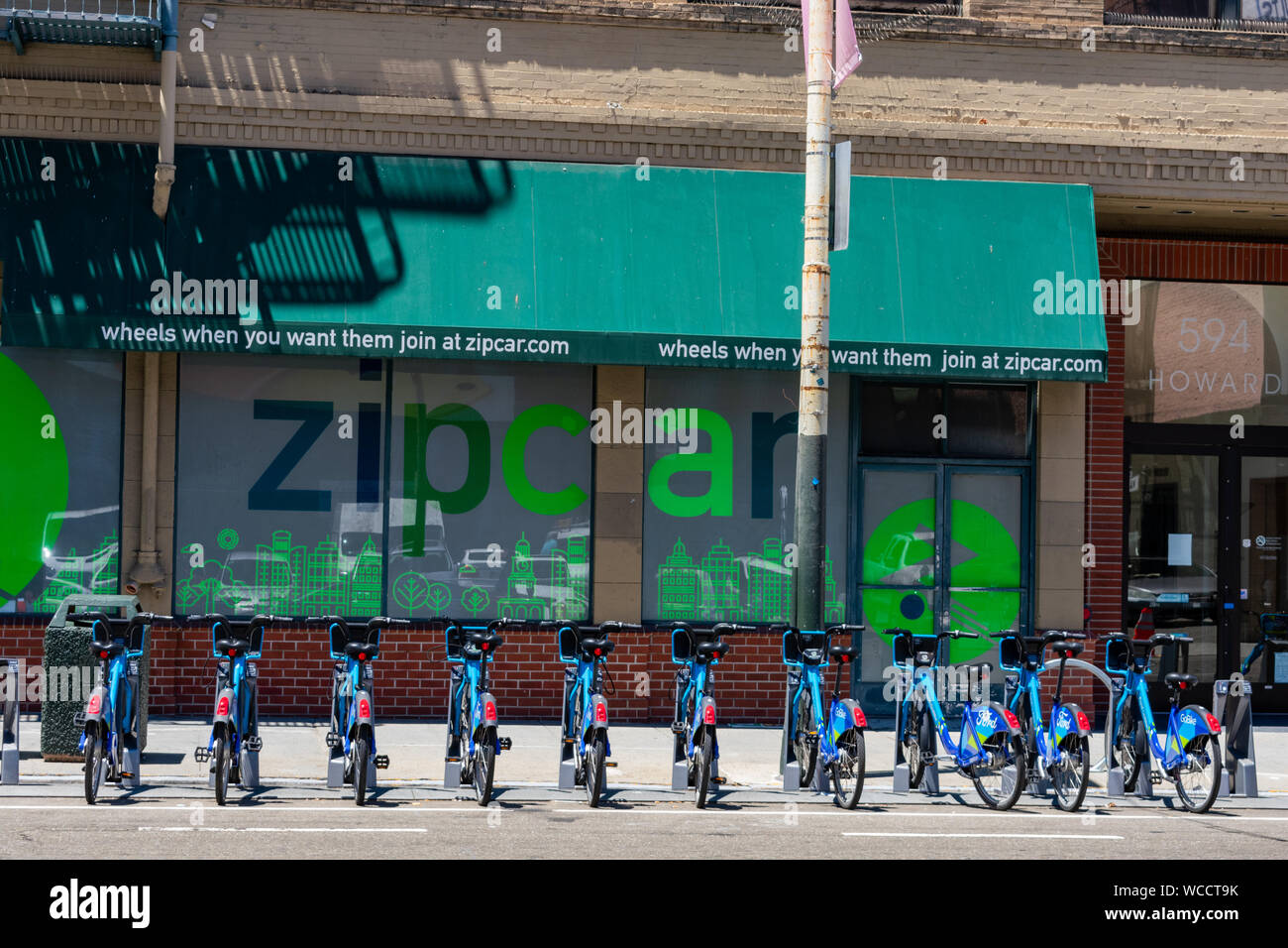 Ford GoBikes Elektrofahrrad parkplatz Station mit einer Werbung für ZipCar Service im Hintergrund Stockfoto