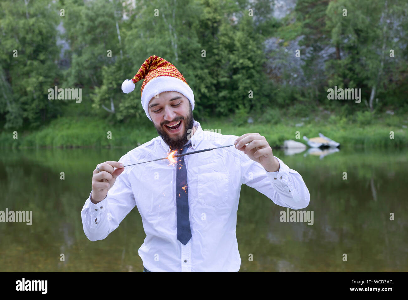 Freudiger Mann in einen Anzug, Krawatte und Neues Jahr oder Santa Hut hält eine wunderkerze. Neue Jahre Corporate Partei Stockfoto