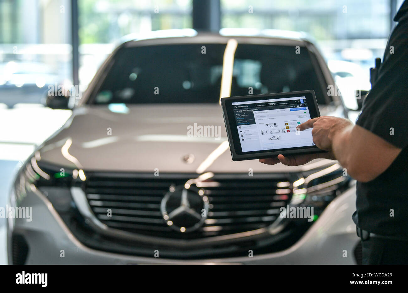 Berlin, Deutschland. 23 Aug, 2019. Abbildung - ein Service-Mitarbeiter hält eine Tablette in die neu erbaute Terminal in der Berliner Mercedes-Welt am Salzufer während eines Service Check der elektrischen SUV Mercedes EQC 400. (Szene.) Der neue Service Lounge komplett an die Anforderungen der elektrischen Mobilität ausgerichtet ist. Foto: Jens Kalaene/dpa-Zentralbild/ZB/dpa/Alamy leben Nachrichten Stockfoto