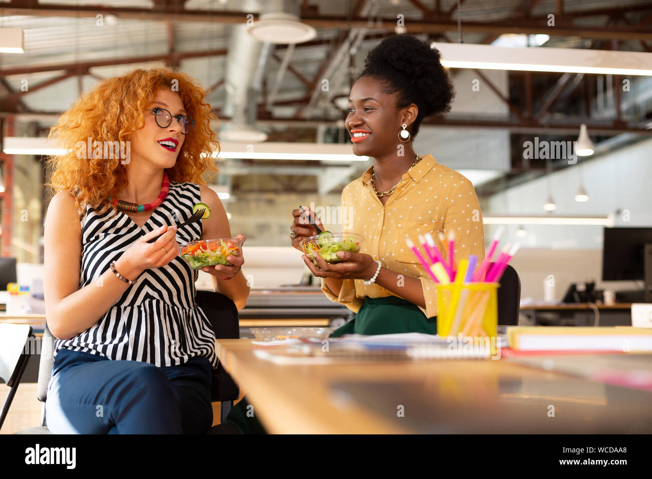 Curly Geschäftsfrau Salat mit dunkelhäutigen Kollegen Stockfoto
