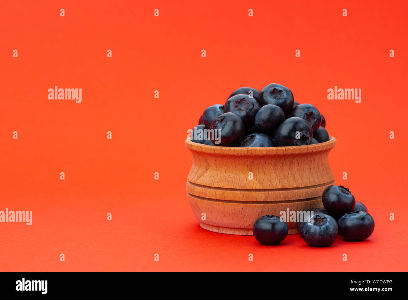 Blaubeeren in Houten auf rotem Hintergrund mit Kopie Raum isoliert Stockfoto