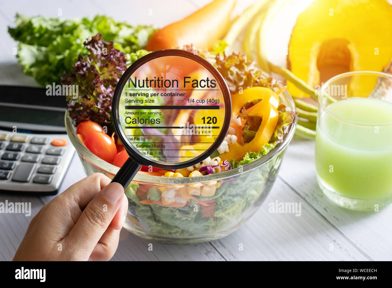 Ernährungswissenschaftliche Informationen Konzept. Hand verwenden Sie die Lupe, um das Bild zu vergrössern, die Einzelheiten der Ernährung Fakten aus der Nahrung zu sehen, Salat Schüssel Stockfoto