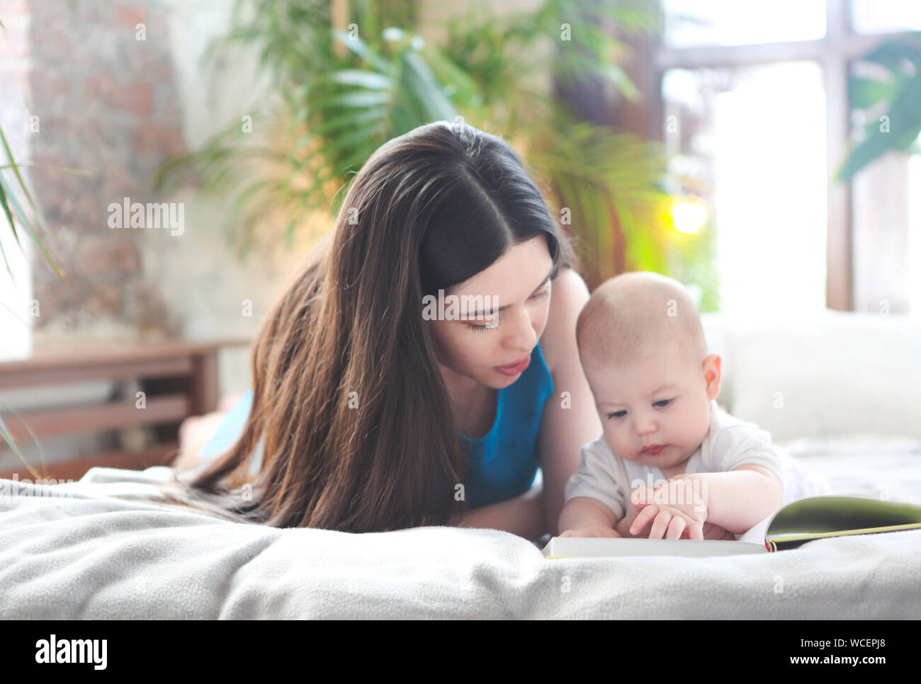Junge Mutter ein Buch lesen mit ihrem kleinen Sohn im Schlafzimmer Stockfoto