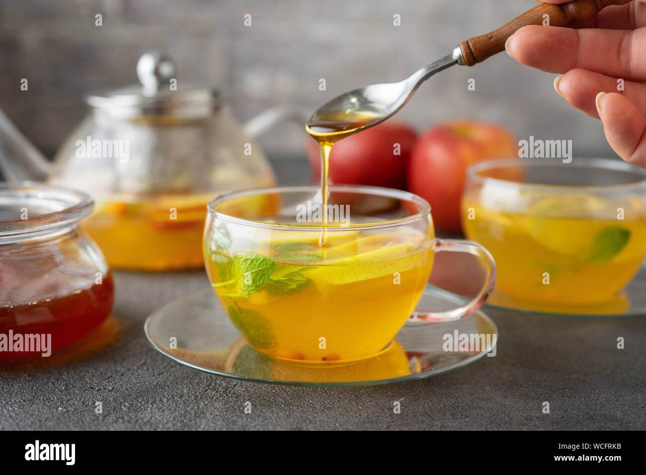 Gießen Honig in Glas Tasse Früchtetee Stockfoto