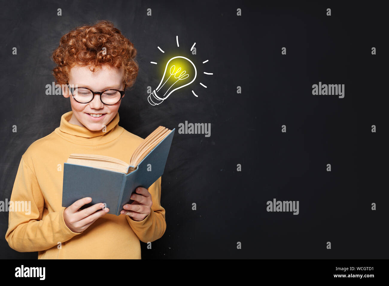 Kind Junge ein Buch lesen, Spaß und Idee Glühbirne auf blackboard Hintergrund im Klassenzimmer Stockfoto