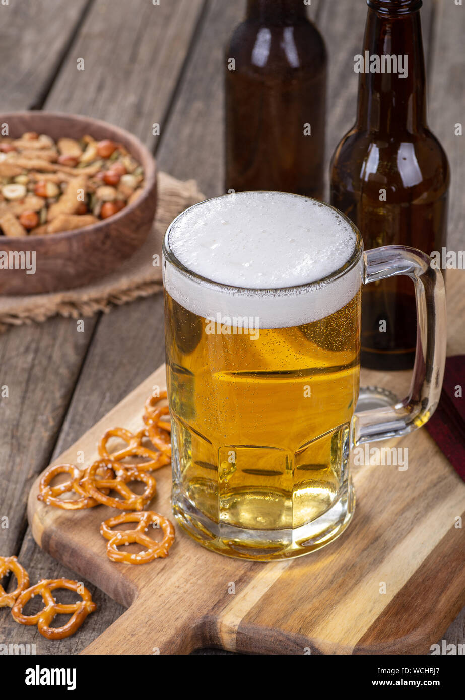Glas Becher Bier mit Snacks auf ein rustikales Holz- Oberfläche Stockfoto