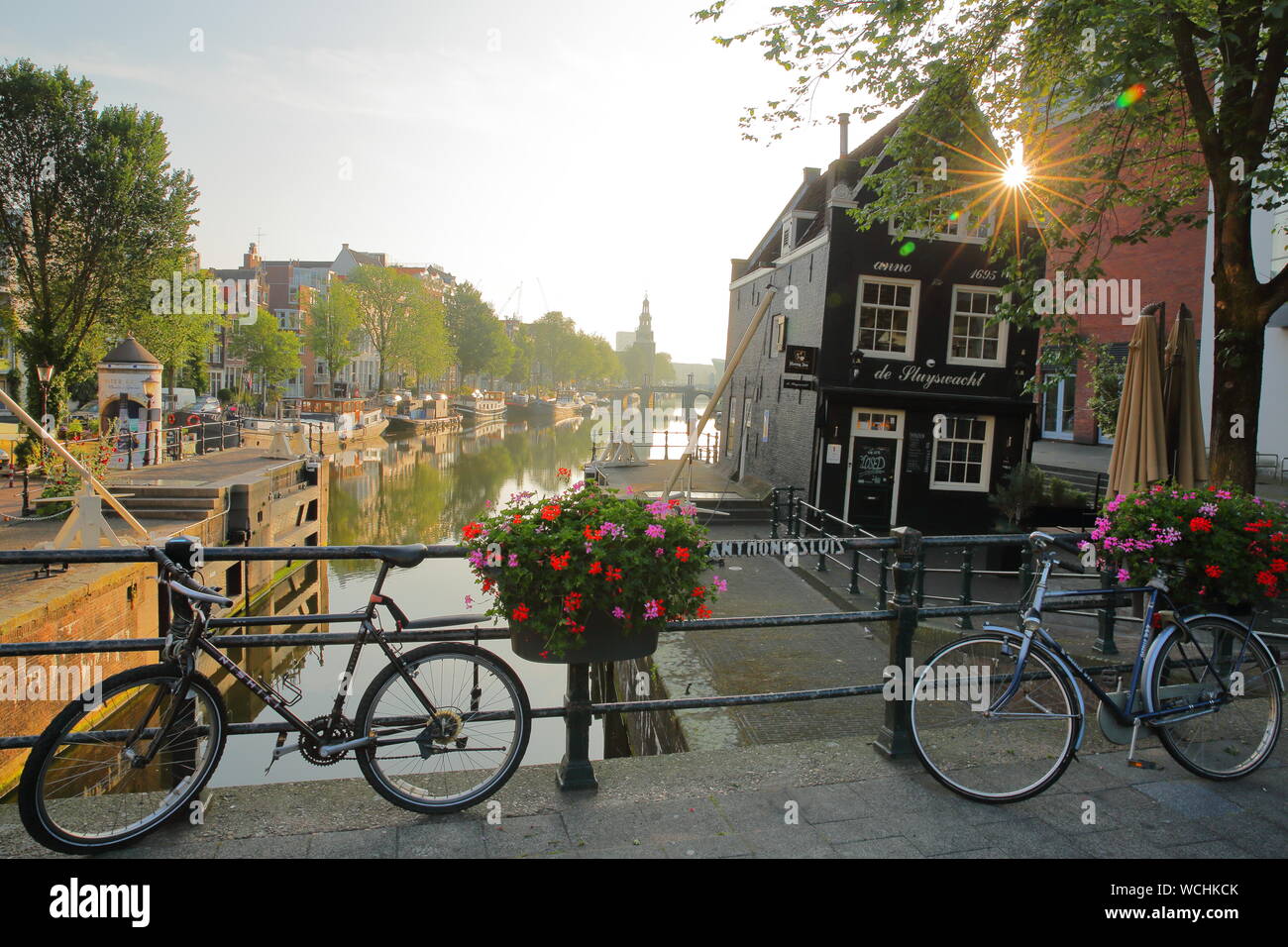 AMSTERDAM, NIEDERLANDE, 17. JULI 2019: Sint Oudeschans Antoniesluis lock, mit Blick auf den Kanal, mit einem schiefen Gebäude (Cafe de Sluyswacht) Stockfoto