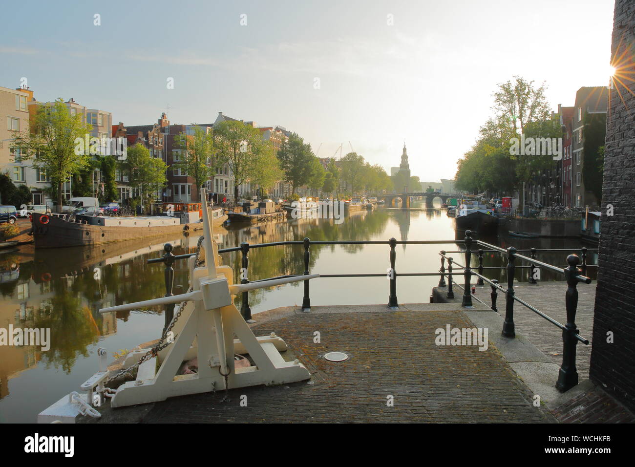 Sint Oudeschans Antoniesluis lock, mit Blick auf den Kanal, mit Reflexionen. Bild am frühen Morgen mit Sonnenstrahlen und Sun Star, Amsterdam, Niederlande Stockfoto