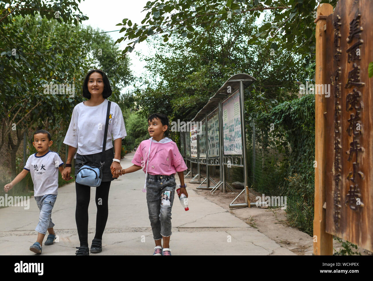 (190828) - KASHGAR, Aug 28, 2019 (Xinhua) - die Dorfbewohner zu Fuß in einer Gasse im Dorf Qianjin in Kashgar, Nordwesten Chinas Autonome Region Xinjiang Uygur, Aug 18., 2019. Wohnungen von duftenden Blüten im Überfluss umgeben, übersichtliche Häuser und Gassen von einem gepflegten Erscheinungsbild, verschiedene Bäume entlang der Straßen, wo die Kinder sich genießen, die pastorale Szene überall in Qianjin Dorf gesehen werden kann. Die idyllische Schönheit in Qianjin Dorf leitet sich aus seiner boomenden Wirtschaft, in der Blume Salima Sultan ist ein Pionier. Salima, ein 60-jähriger Dorfbewohner, entwickelte sich die Vorliebe der Strömung Stockfoto