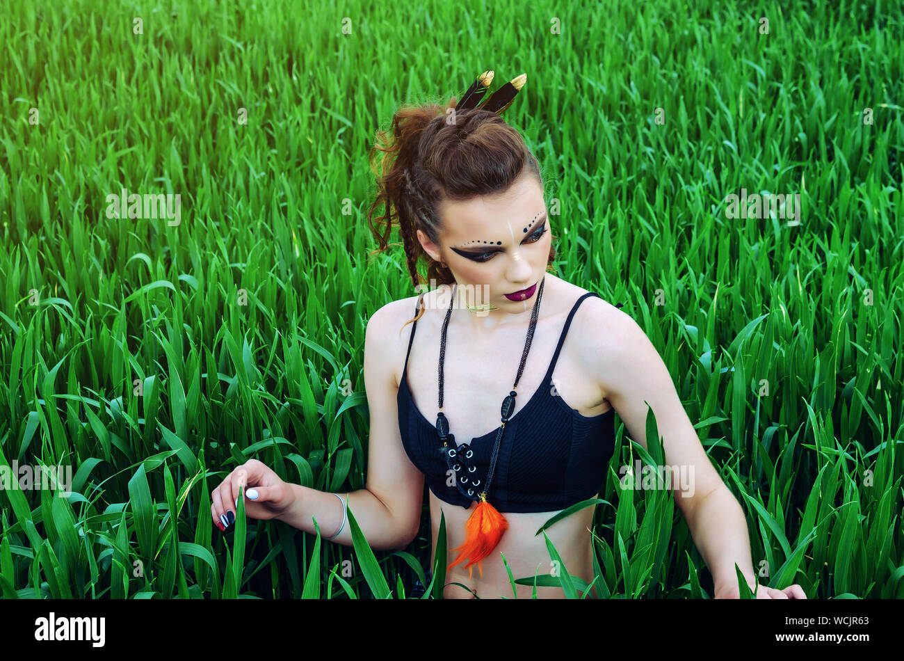 Aggressive Make-up Girl, amazon Charakter in ein grünes Weizenfeld. Feminismus, der Unabhängigkeit, der Stamm. Stockfoto