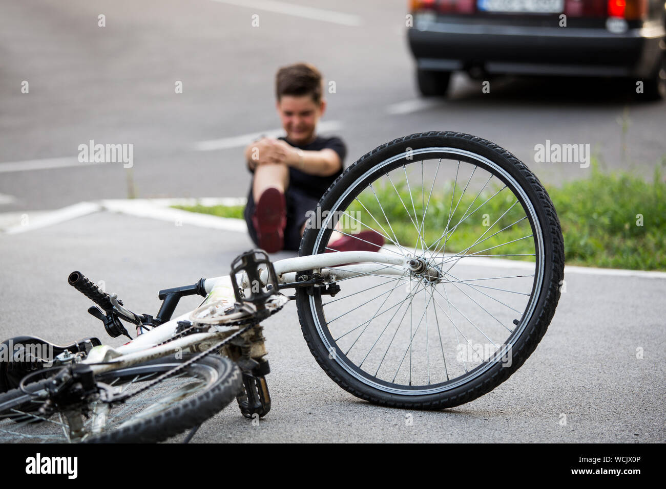 Teenager gibt es eine Knieverletzung, wie die Fahrrad fällt beim Reiten. Kind verletzt sein Bein, nachdem sie weg von seinem Fahrrad Stockfoto