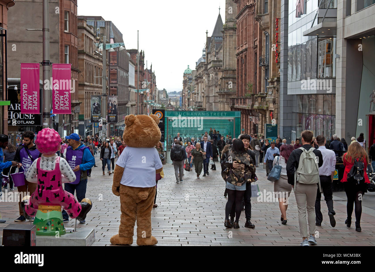 Buchanan Street Glasgow, Schottland, Großbritannien. 28 Aug, 2019. Käufer und Besucher wandern entlang in die dunstige Sonnenschein durch die pedestriansed Buchanan Street in Glasgow. Der Donald Dewar statue stolz an der Oberseite der Straße steht, der erste Minister von Schottland und ein Fürsprecher der Scottish Devolution, würde man mich fragen, was seine Gedanken würden zur heutigen breaking news, dass der britische Premierminister Boris Johnson die Königin gebeten hat das britische Parlament ab Mitte auszusetzen - September. Stockfoto