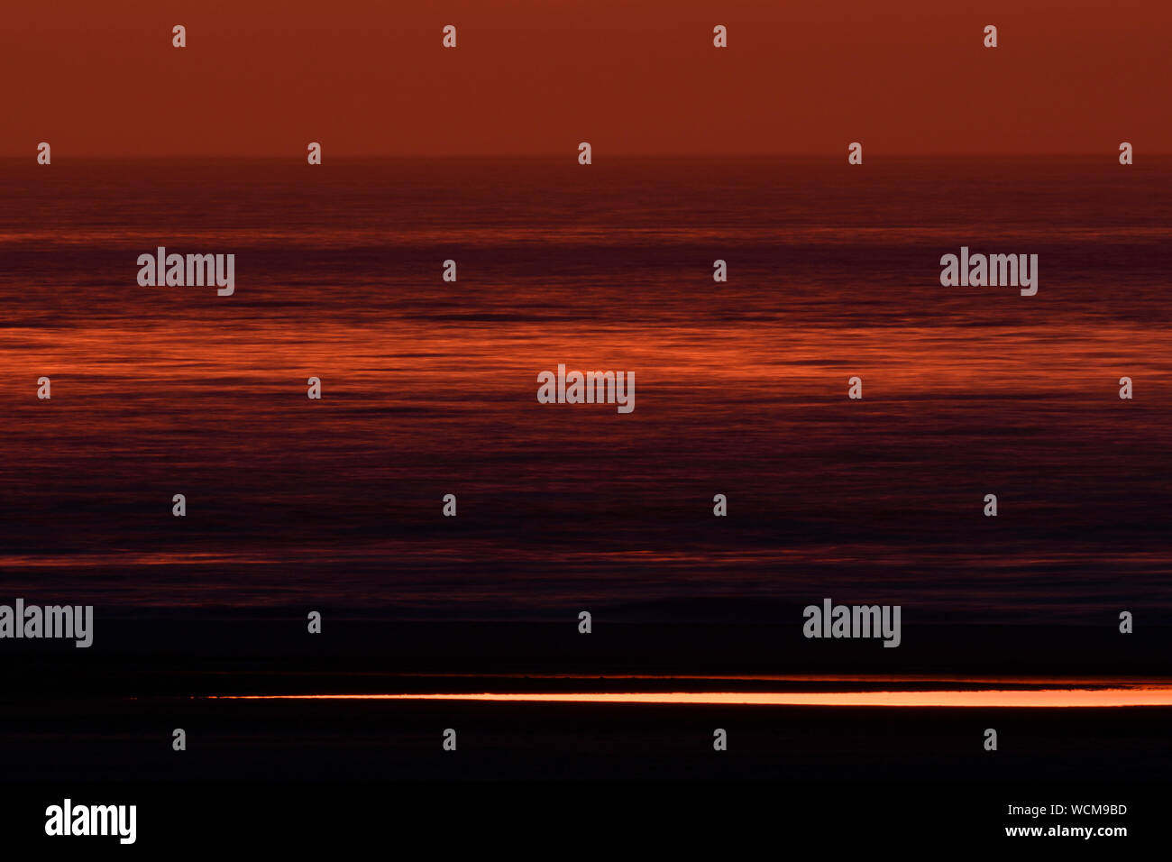 Lange Exposition von rot und orange gefärbten Himmel, Meer und Strand nur wenige Minuten nach Sonnenuntergang, Ende der Tag, voller Atmosphäre und Stille, Europa. Stockfoto