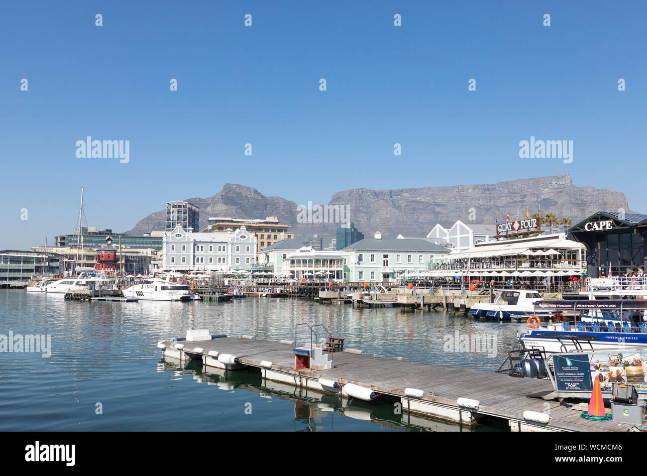 Hafen von Kapstadt und der V & A Waterfront mit Restaurants, Geschäften und einem Blick auf die Devils Peak und Tafelberg an einem sonnigen Wintertag Stockfoto