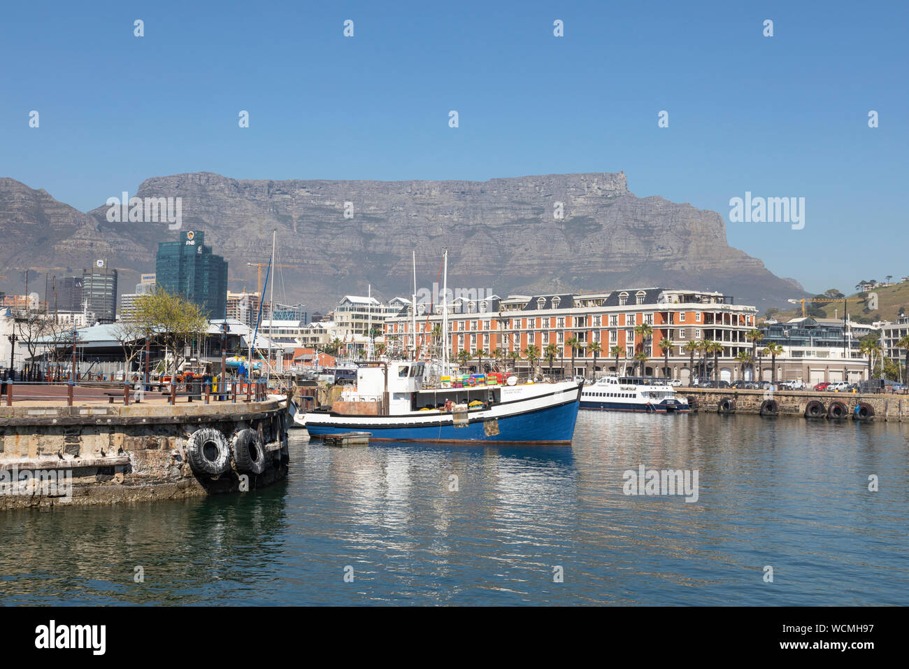 Fischerboot im Hafen von V&A Waterfront, Cape Town Südafrika, mit dem Tafelberg hinter, einem Unesco Weltnaturerbe Stockfoto