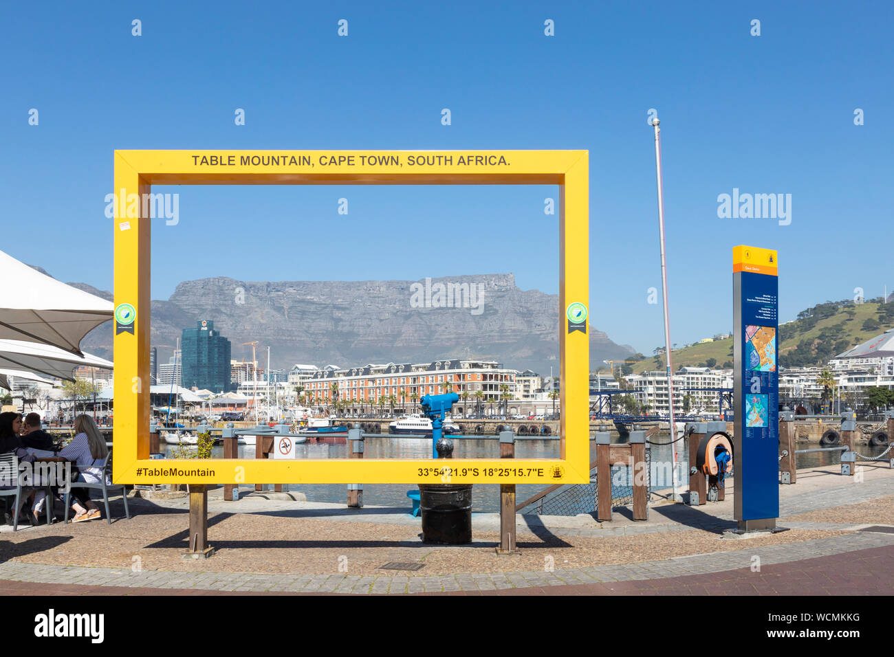 Der gelbe Rahmen framing Tafelberg an den Kais, V & A Waterfront, Cape Town, Südafrika mit Touristen essen in einem Restaurant Stockfoto