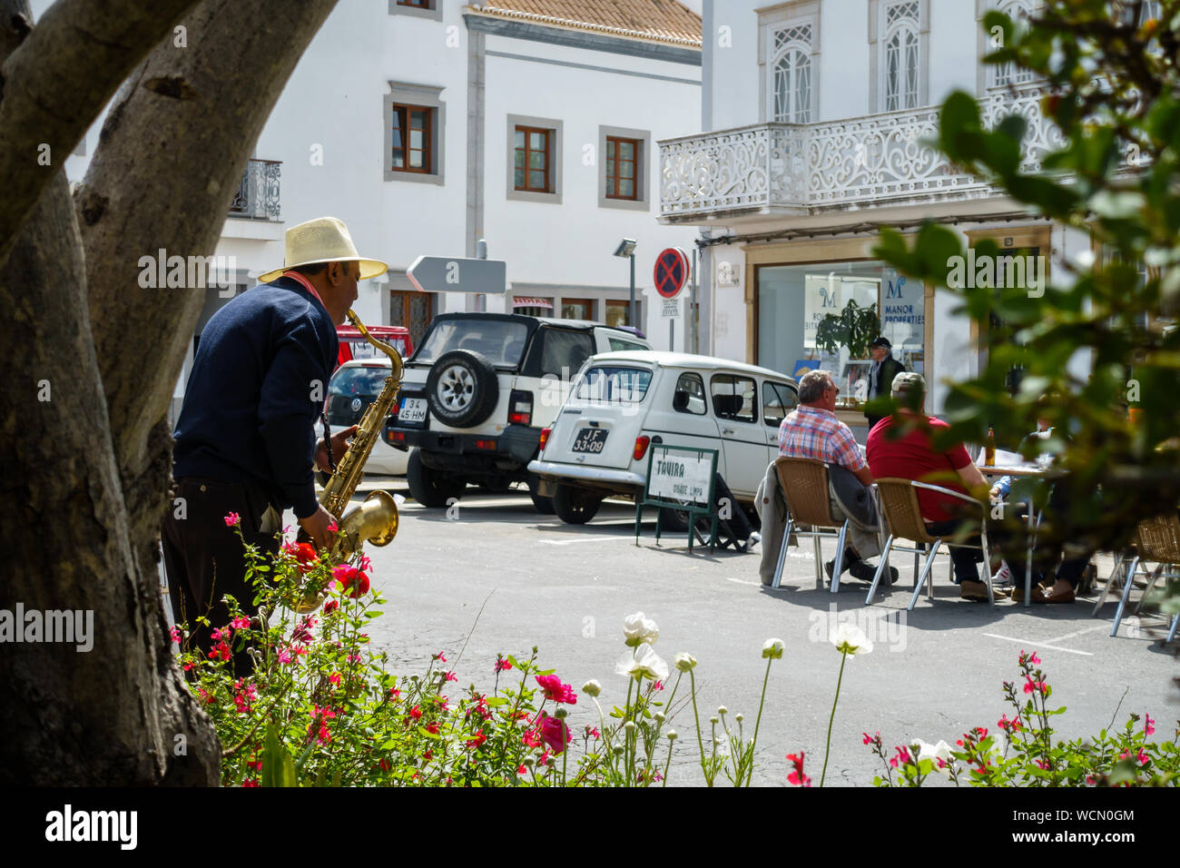 TAVIRA, PORTUGAL - 23. MÄRZ 2018: Ein männlicher osteuropäischen Straßenmusiker spielt Jazz Musik mit Saxophon für Touristen (Rahmen der Pflanzen) Stockfoto