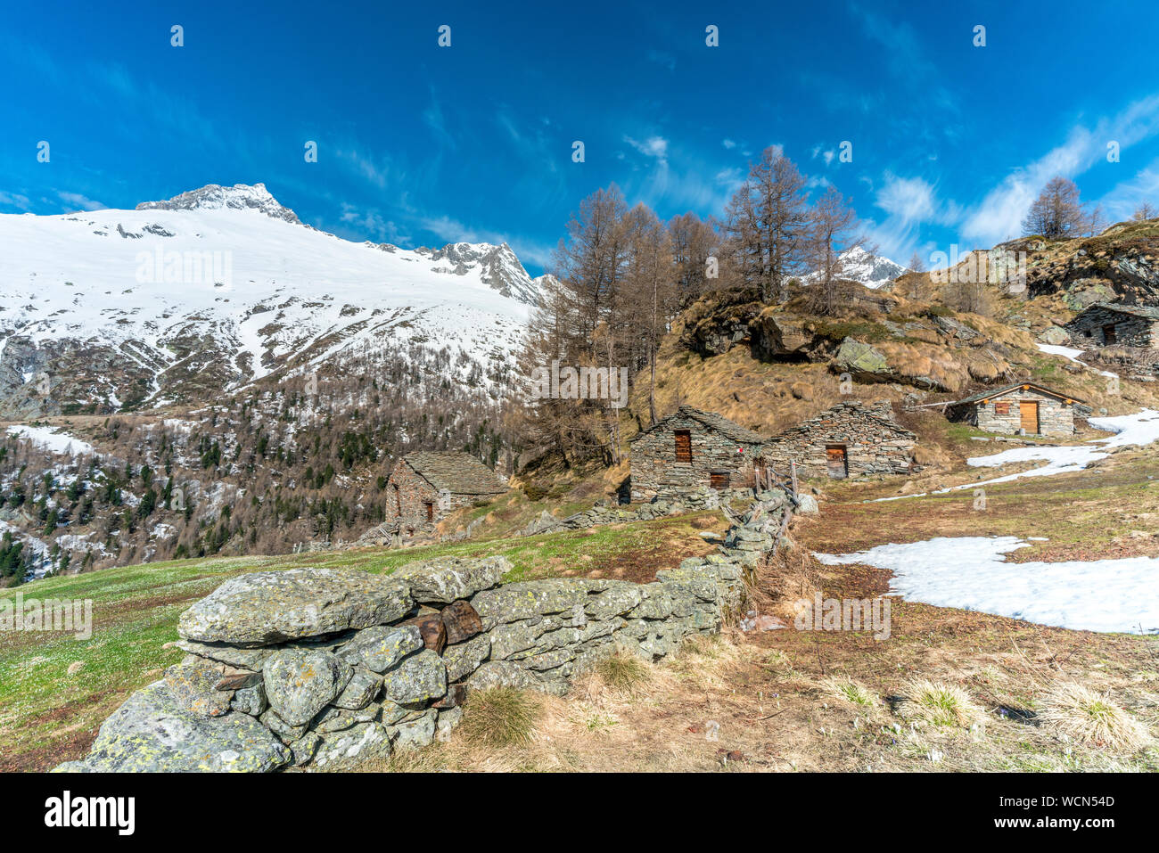 Steinhütten durch die schneebedeckten Gipfel im Frühjahr umgeben, Alpe Oro, Valmalenco, Veltlin Sondrio Provinz, Lombardei, Italien Stockfoto