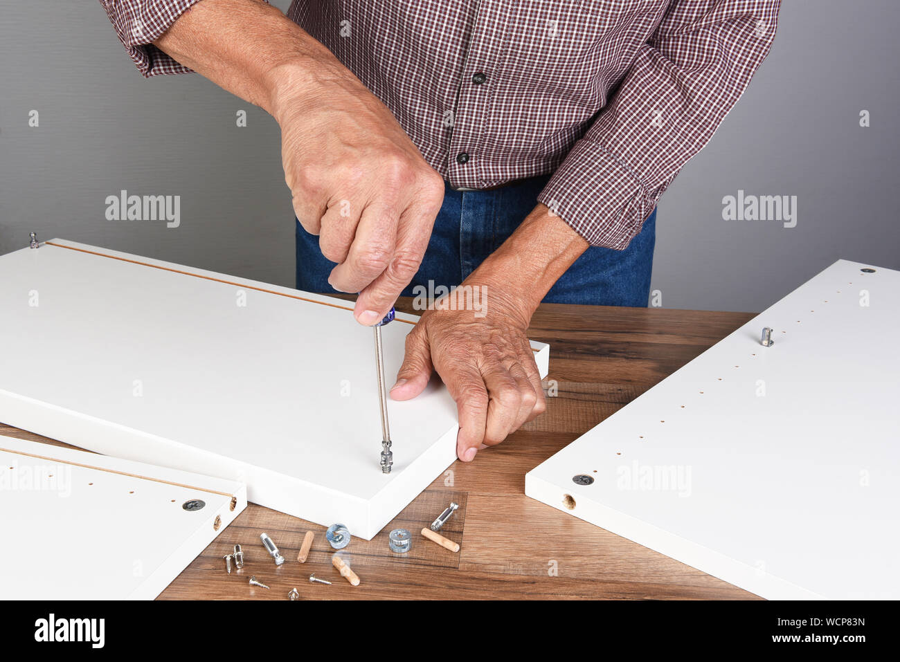 Ein Mann der Montage eines DIY-Möbel. Person wird mit einem Schraubendreher einsetzen ein Stück Hardware. Stockfoto