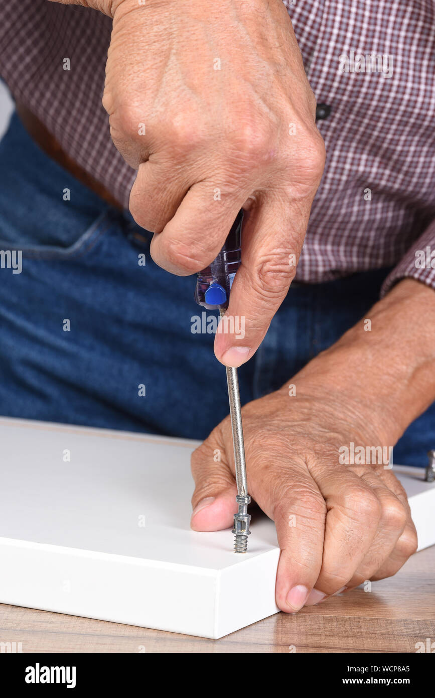 Nahaufnahme von einem Mann Montage eines DIY-Möbel. Person wird mit einem Schraubendreher einsetzen ein Stück Hardware. Stockfoto