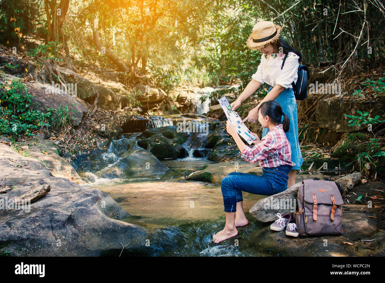 Frau und Mädchen teilen Karte per Stream im Wald Stockfoto