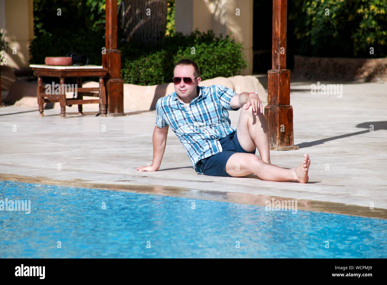 Touristen und Reisende sitzt, Posieren und zur Festlegung neben Schwimmbad des Hotel Resort, genießt Aussicht auf Umgebung und Ruhe in sonniger Tag. Stockfoto