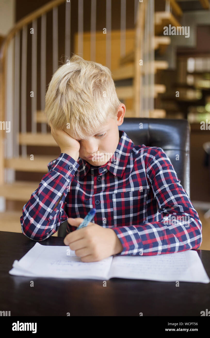 Traurige Schüler schreiben auf Notebook zu Hause. Hausaufgaben. Bildung, Kindheit und Personen Konzept Stockfoto