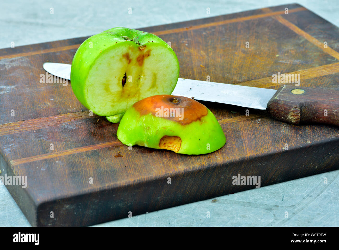 Apple schneiden Sie mit einem morschen Bereich auf Holz Schneidebrett mit Messer Stockfoto