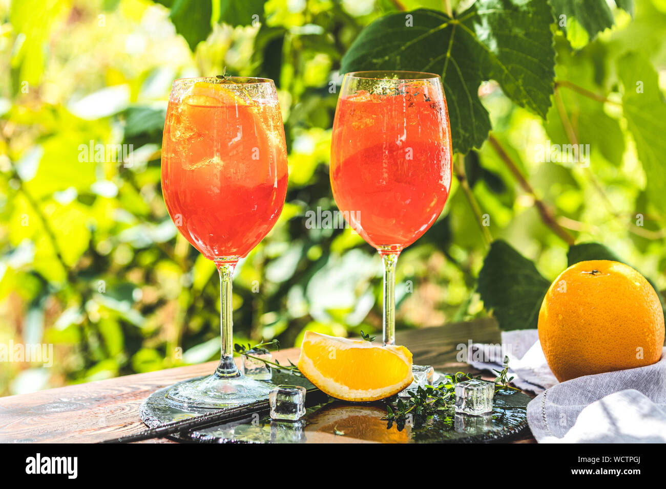 Zwei Aperol Spritz Cocktail in großen Wein Glas mit Orangen, Sommer  Italienisch frische Alkohol kaltes Getränk. Sonniger Garten mit Weinberg  Hintergrund, Sommer Stimmung Stockfotografie - Alamy