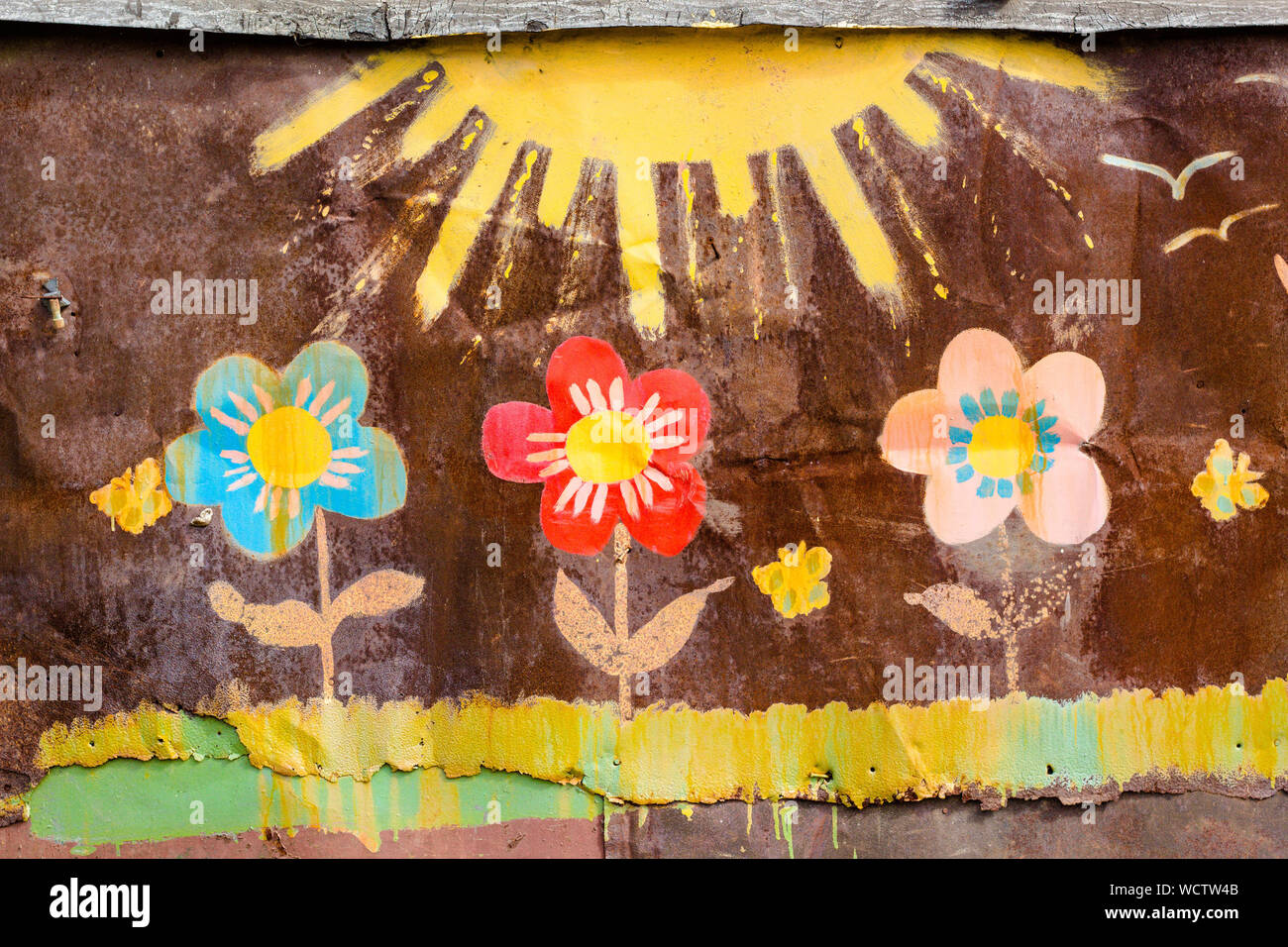Zeichnung Blumen und die Sonne an der Wand. Die Mauer ist aus Eisen, und das Bild wird mit hellen Farben gemalt. Stockfoto