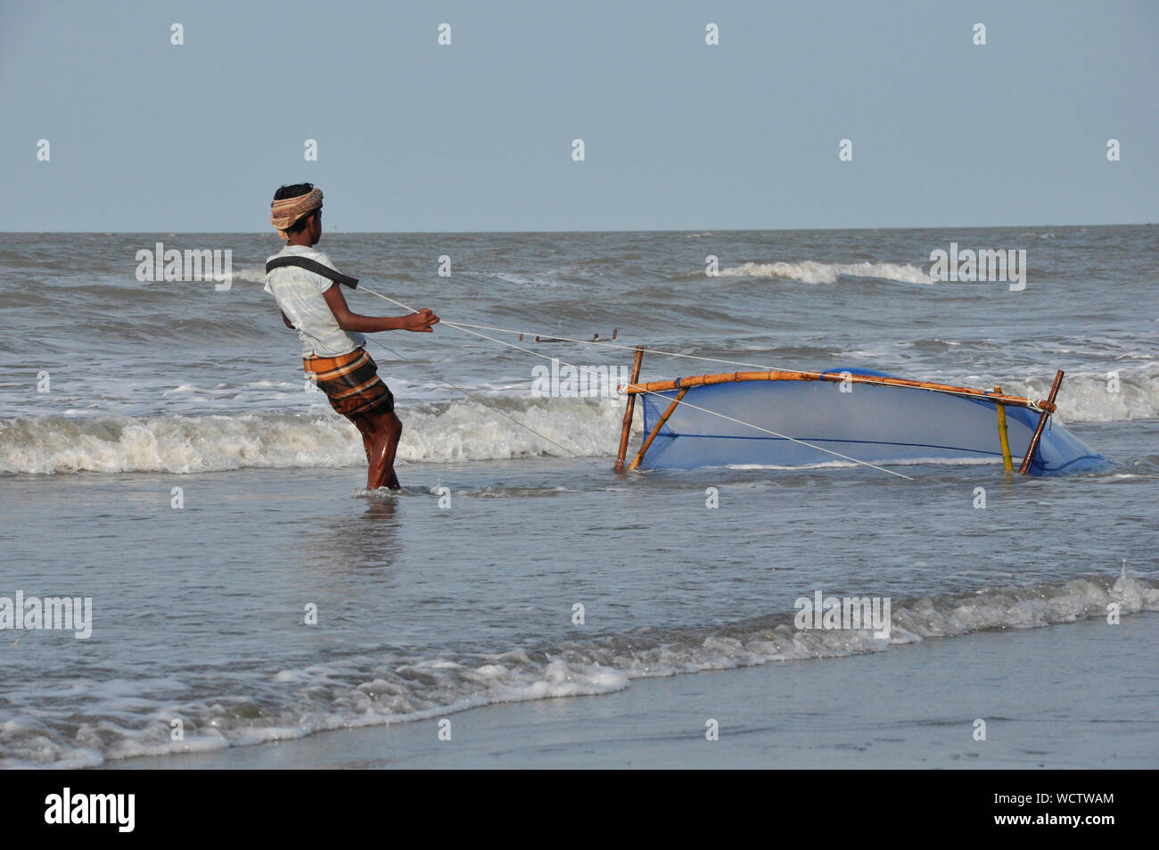Ein junger Mann Fänge Garnelen mit einem Netz von der Bucht von Bengalen, in Kuakata, Patuakhali, Bangladesch. 27. April 2010. Ein beliebtes Touristenziel, Kuakata ist einer der seltensten Spots der Welt, dass die volle Sicht auf den Sonnenaufgang und Sonnenuntergang über der Bucht von Bengalen bietet. Stockfoto