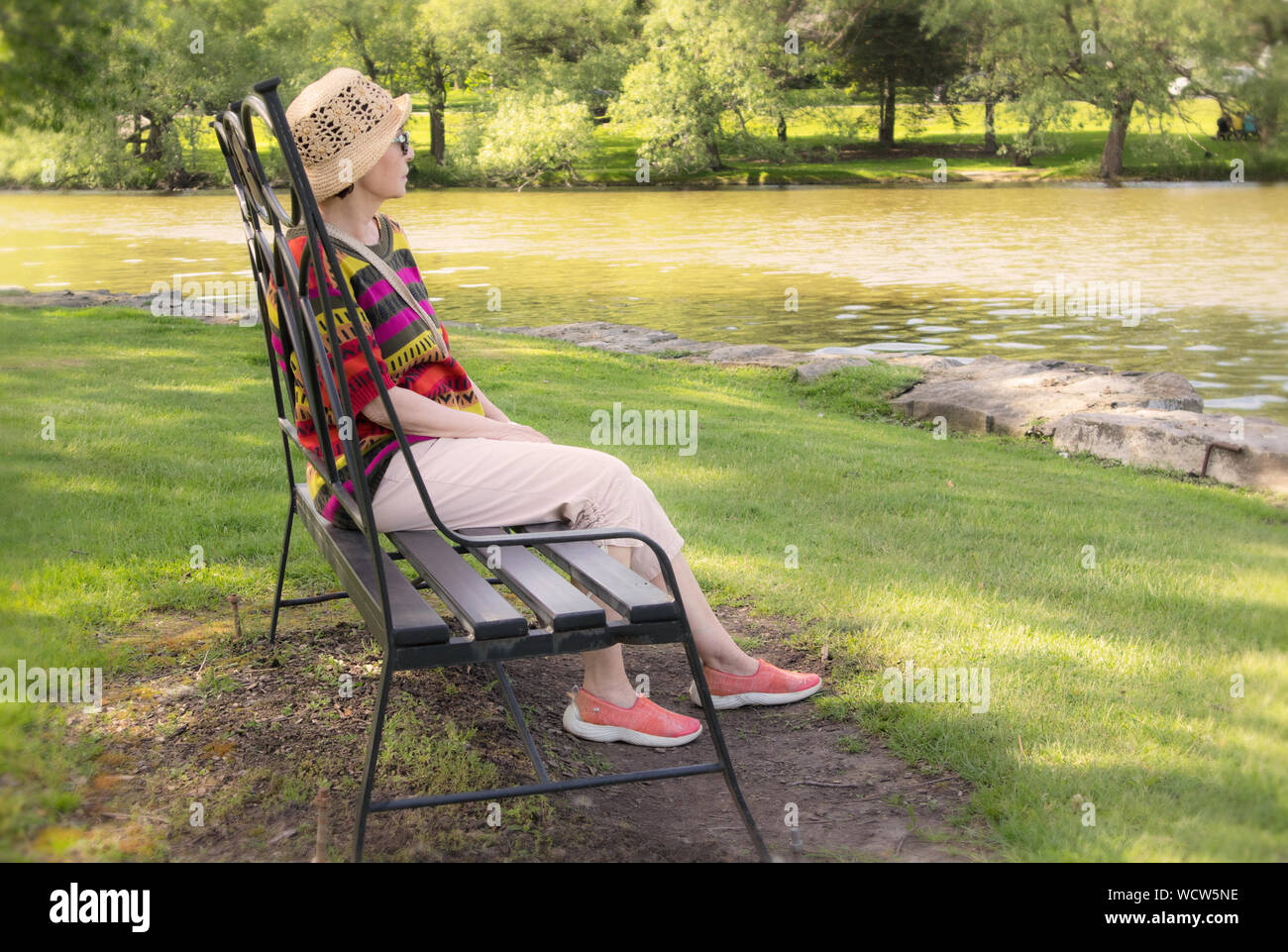 Eine reife Frau auf einer Parkbank und beobachtete vor ihr, den See. Stockfoto