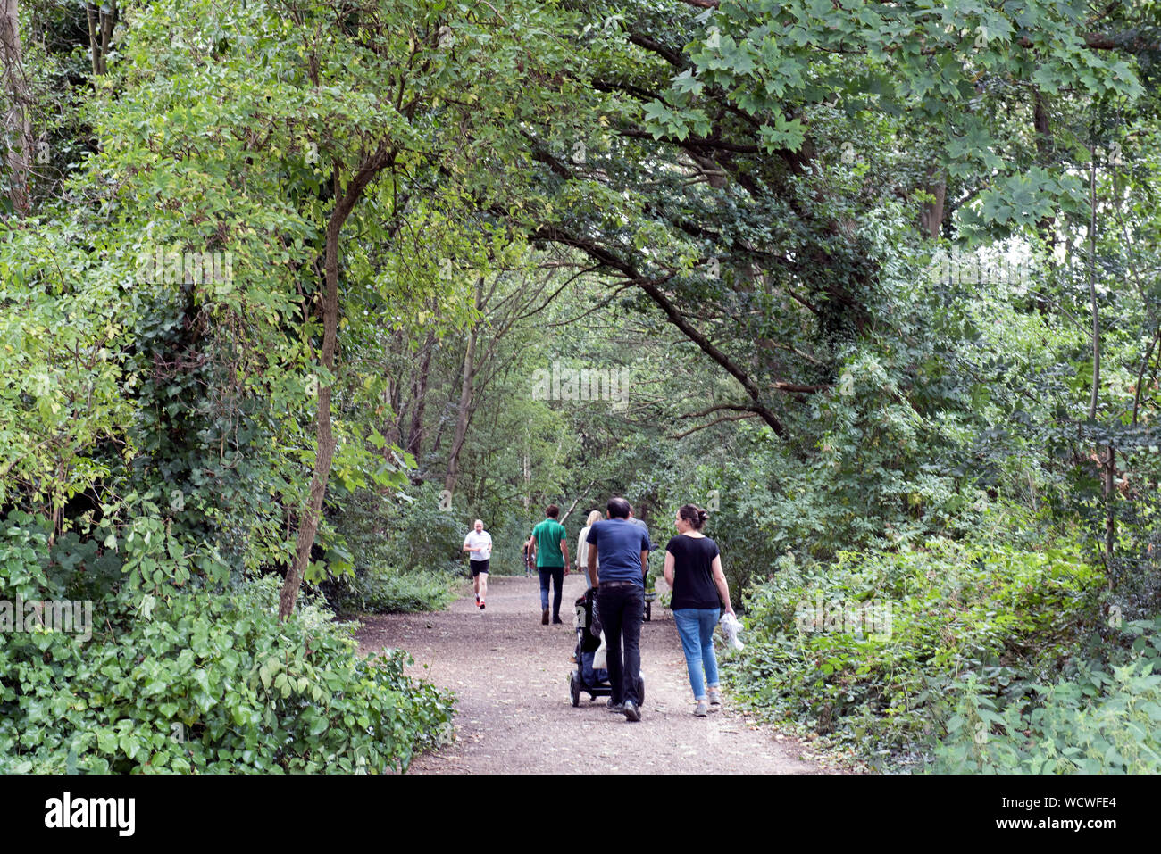 Menschen wandern und joggen entlang der Parklandschaft spazieren, eine stillgelegte Bahnstrecke jetzt ein urban Nature Reserve, London Borough von Haringey Stockfoto