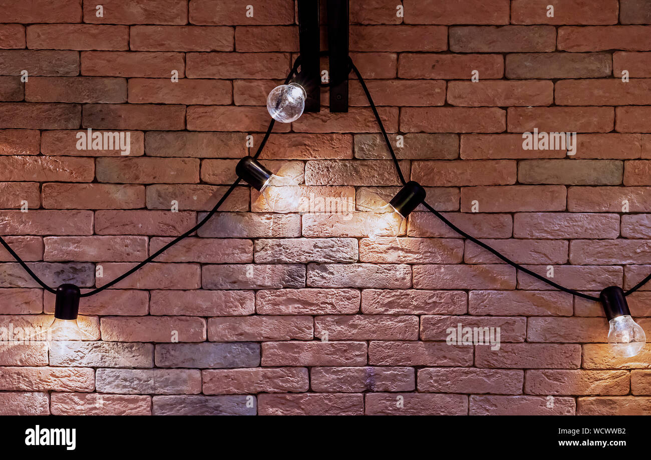Girlande von elektrischen Lampen auf einer Ziegelwand Hintergrund. Loft Interieur. Stockfoto